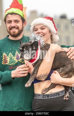 Centinaia di nuotatori si tuffano in un mare turbolento il giorno di Natale sulla spiaggia di Brighton come parte dei festeggiamenti con un tuffo rinvigorente. Brighton, Foto Stock