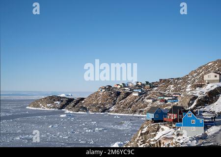 Case colorate aggrappate al lato della montagna sull'isola di Uummannaq, Groenlandia occidentale. Foto Stock