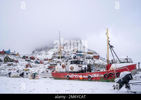 Le barche da pesca congelate nel ghiaccio marino nel porto dell'isola di Uummannaq, nella Groenlandia occidentale Foto Stock