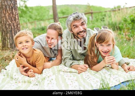 Genitori felici con bambini sdraiati in coperta al campeggio durante le vacanze estive Foto Stock