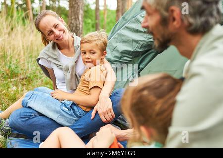 Donna sorridente che parla con l'uomo mentre passa il tempo libero in campeggio durante le vacanze Foto Stock