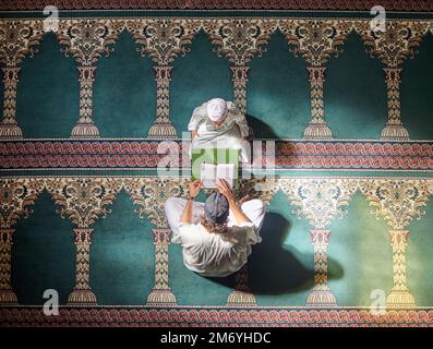 I musulmani pregano, bambini o uomini in preghiera con il Corano per la pace, la consapevolezza o il sostegno di Allah nella moschea sacra. Vista dall'alto, bambino islamico o persona che studia Foto Stock