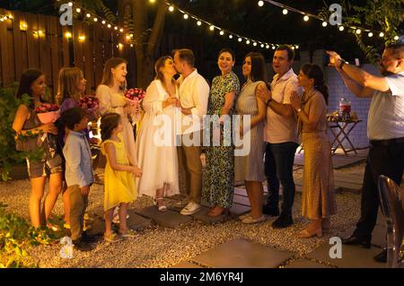 Cerimonia di matrimonio aperta. Sposa, sposo, uomo migliore, le bridesmaids intorno. Celebrazione del matrimonio all'aperto. Bouquet di fiori, anelli, voti. Amici felici. Celebrat Foto Stock