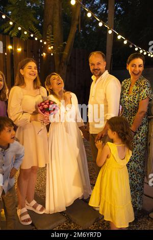 Cerimonia di matrimonio aperta. Sposa, sposo, uomo migliore, le bridesmaids intorno. Celebrazione del matrimonio all'aperto. Bouquet di fiori, anelli, voti. Amici felici. Celebrat Foto Stock