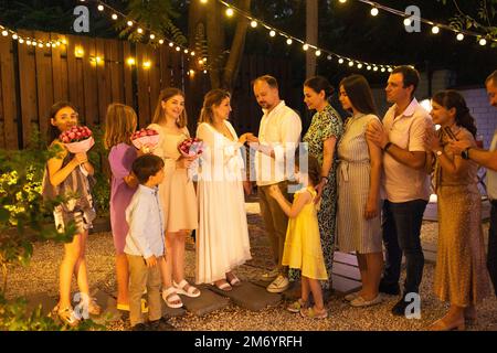 Cerimonia di matrimonio aperta. Sposa, sposo, uomo migliore, le bridesmaids intorno. Celebrazione del matrimonio all'aperto. Bouquet di fiori, anelli, voti. Amici felici. Celebrat Foto Stock