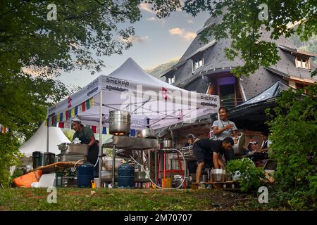 Giovani che cucinano piatti tipici nepalesi in una cucina da campo nel giardino della Maison des Artistes durante il Cosmo Jazz Festival, Chamonix, Francia Foto Stock