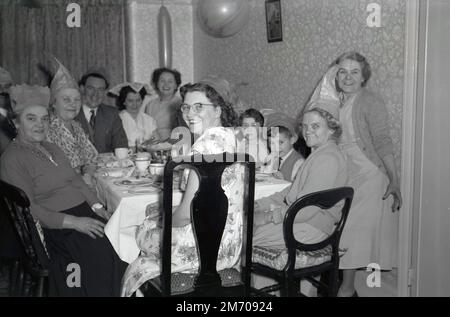 1950s, storico, sorrisi grandi come una famiglia si siede intorno ad un tavolo che ha loro pranzo di Natale, Inghilterra, Regno Unito. Foto Stock