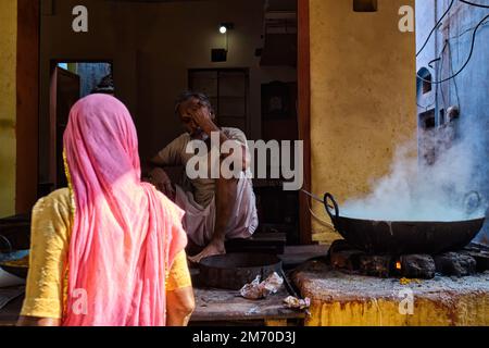 Pushkar, India - 7 novembre 2019: Donna che acquista da strada cibo stalla cuoco cottura dolce puri pane e rabi dolce, condensato a base di latte piatto Foto Stock