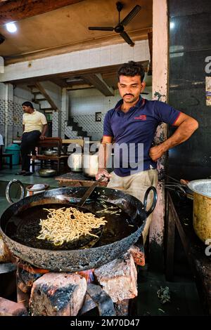 Pushkar, India - 7 novembre 2019: Cuoco indiano fa Murukku cibo di strada fresco. Fritto abbondante gustoso snack vegetariano croccante in olio. Tradizionale delizioso Foto Stock