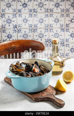 cozze in vino bianco e succo di limone in una caserola di ghisa blu Foto Stock