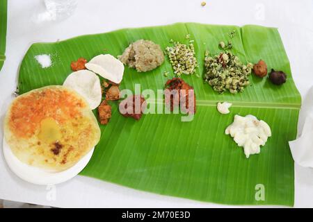 I pasti dell'India del sud sono serviti in una foglia di banana. Antipasti vegetariani con diversi tipi di cibo delizioso come obbattu e insalate Foto Stock