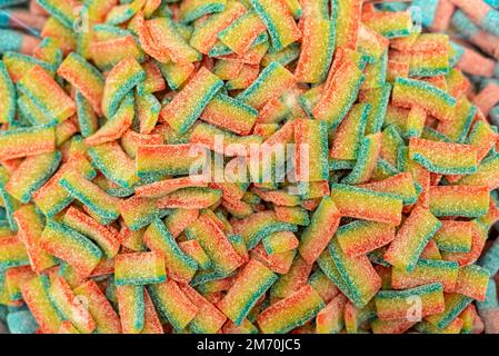 molte caramelle di marmellata colorate disposte su una superficie piana; dessert per le vacanze; dolci regali per i bambini; consistenza e sfondo con piccole caramelle Foto Stock