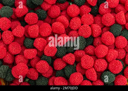 molte caramelle di marmellata colorate disposte su una superficie piana; dessert per le vacanze; dolci regali per i bambini; consistenza e sfondo con piccole caramelle Foto Stock