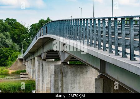 Ponte sul fiume tra alberi verdi in una giornata nuvolosa estiva. Fiume. Foto Stock