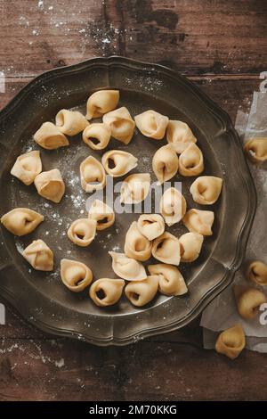 Tortellini su un piatto su sfondo di legno Foto Stock