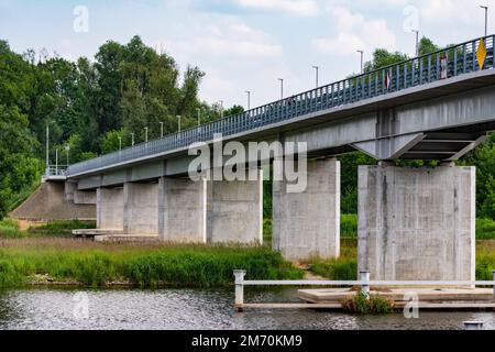 Ponte sul fiume tra alberi verdi in una giornata nuvolosa estiva. Fiume. Foto Stock