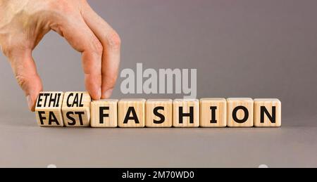 Simbolo di moda etico o veloce. Concetto di parole moda veloce ed etica su cubi di legno. Mano uomo d'affari. Splendido sfondo grigio. Business Foto Stock