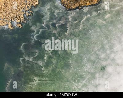 Vista aerea di un lago ghiacciato. Sfondo ghiaccio foglio. Onde congelate sul lago. Sfondo ghiaccio. Copertura di ghiaccio su un lago nella Polonia meridionale nel Bieszczady Foto Stock