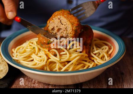 Primo piano di un uomo che mangia un piatto di polpette con spaghetti Foto Stock