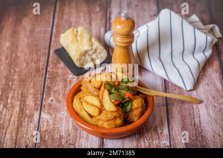 Primo piano di una porzione di polpette con patatine fritte in una casseruola di terracotta con shaker di pepe coperto e pane Foto Stock