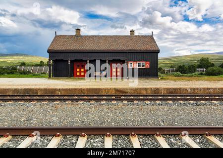 Uomo seduto solo su una panchina che guarda i binari, la storica stazione ferroviaria di Fokstura, immagine simbolica in attesa, in viaggio, in strada Foto Stock