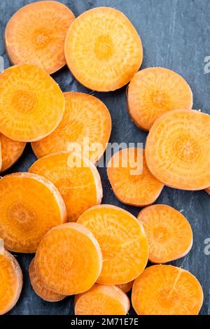 Macro di carote arancioni a fette su uno sfondo di ardesia. Foto Stock