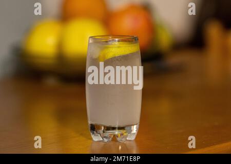 Bicchiere con acqua frizzante e limone. sfondo di legno, sfondo di frutta di agrumi. Rinfrescante Gin e bevanda tonica con limone e ghiaccio. Foto Stock