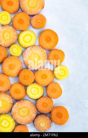 Primo piano di carote gialle e arancioni tagliate, visualizzate in alto in un motivo geometrico con spazio per il testo. Foto Stock