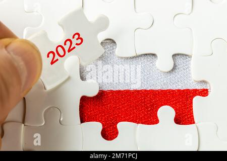 Anno 2023 e bandiera polacca in un puzzle, concetto, problemi economici della Polonia Foto Stock
