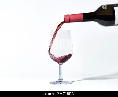 Un bicchiere di vino. mettere il vino rosso. Bottiglie di vino e bicchieri. Cultura del mangiare e del bere. Bevande alcoliche. Ripresa isolata su sfondo bianco. Foto Stock