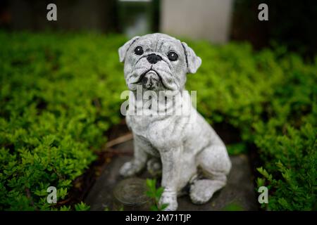 un cane figura coraggiosamente guardia di una tomba in un cimitero Foto Stock