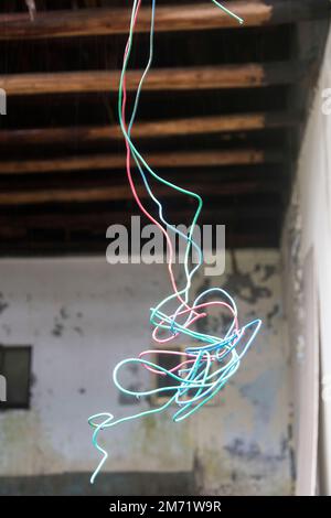 Pericoloso cablaggio difettoso che pende sul soffitto da una vecchia casa Foto Stock