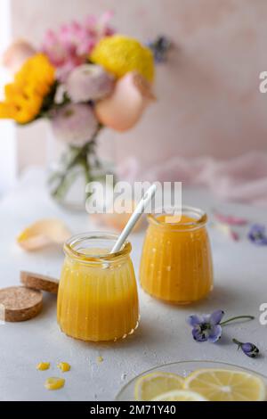 Cagliata di limone in vasetti di vetro decorati con fiori primaverili e pastelli Foto Stock