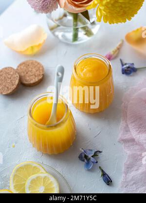 Cagliata di limone in vasetti di vetro decorati con fiori primaverili e pastelli Foto Stock