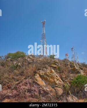 torri di comunicazione sulla cima di una montagna nel mezzo della foresta desertica, cielo blu nei giorni estivi, nessuna gente, rocce e palme Foto Stock
