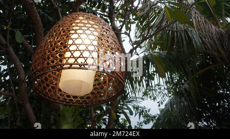 Lampada di lampione da coperta tessuta di bambù appesa nell'albero Foto Stock