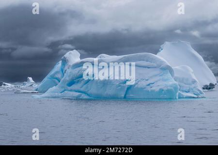 Grandi iceberg galleggiano nell'acqua ferma dell'Antartide, con ghiaccio blu e strati di neve. Foto Stock