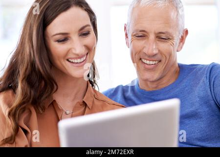 Questo è il modo in cui ci teniamo in contatto con il resto della famiglia. una coppia felice a casa utilizzando il tablet digitale per chattare con la famiglia. Foto Stock
