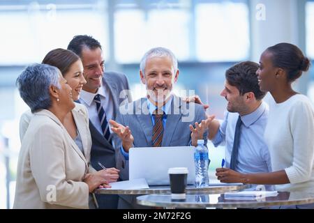 Sulla loro strada per un successo ancora maggiore. Un colpo corto di un gruppo vario di uomini d'affari che hanno una riunione. Foto Stock