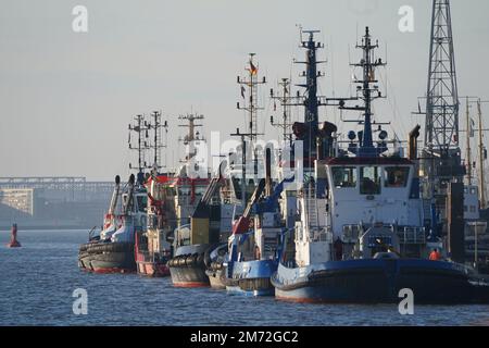 PRODUZIONE - 03 gennaio 2023, Amburgo: Rimorchiatori ormeggiati presso il nuovo ponte di Tugboat nel porto. Il porto di Amburgo sull'Elba è un porto universale per tutti i tipi di merci e di gran lunga il più importante luogo di movimentazione merci in Germania. Ogni anno, circa 130 milioni di tonnellate di merci di mare passano oltre i bordi del molo attraverso un buon 50 impianti di movimentazione, e circa 290 ormeggi offrono spazio per navi di tutte le dimensioni - da contenitori particolarmente grandi e navi portarinfuse, da petroliere e petroliere chimiche a navi di alimentazione e interne. (A dpa 'il porto di Amburgo - tedesco motore di lavoro in sconvolgimento') Foto: Marcus Brandt/ Foto Stock