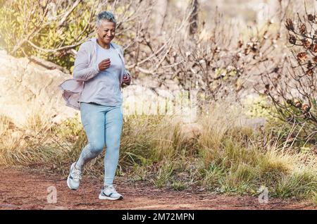 Running, fitness e donna anziana in natura per l'allenamento maratona, la salute sportiva e il cardio di pensione in Indonesia. Sorridere, allenarsi e gli anziani felici Foto Stock