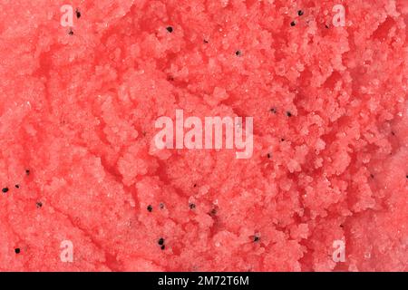Struttura dello scrub corpo con zucchero o sale. Scrub rosso rosa - prodotto per la cura della pelle con estratto di frutta come sfondo cosmetico con spazio copia. Foto macro Foto Stock