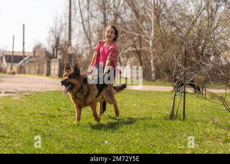 bambina che corre con il suo pastore tedesco animale domestico Foto Stock