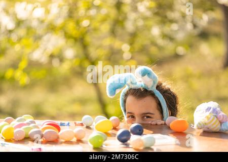 Felice ragazza teen indossare coniglietto orecchie con le uova di Pasqua in giardino Foto Stock