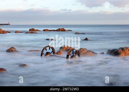 Old chaldron Wagon Wheels sulla spiaggia chimica con il faro di Seaham Harbour Beyond, Durham Heritage Coast, Seaham, County Durham, Regno Unito Foto Stock