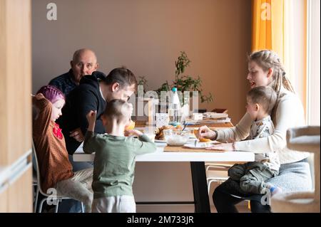 Famiglia multi generazione che mangia il pasto intorno al tavolo della cucina Foto Stock