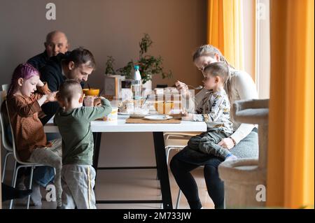 Famiglia multi generazione che mangia il pasto intorno al tavolo della cucina Foto Stock