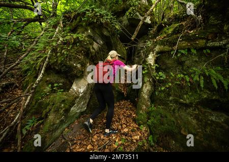 donna scogliera in montagna, donna con zaino in montagna Foto Stock