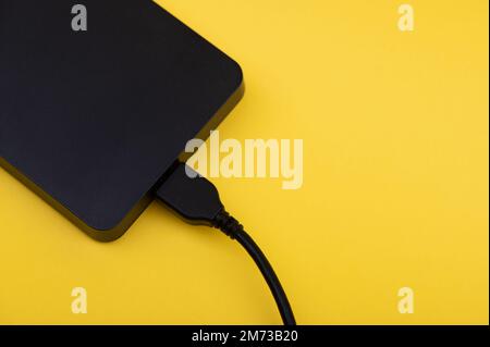 Unità disco rigido portatili esterne nere isolate su sfondo giallo Foto Stock