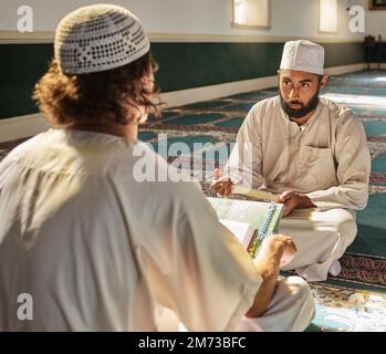 Quran, musulmano e moschea con un imam che insegna a uno studente di religione, tradizione o cultura durante l'eid. Islam, libro o culto con un religioso Foto Stock